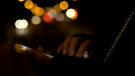 Female-typing-on-smartphone-standing-in-illuminated-night-city,-appointment