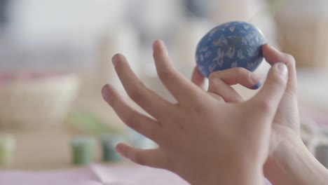 Unrecognized-little-girl-painting-a-heart-on-the-Easter-egg-using-a-small-brush-close-up.