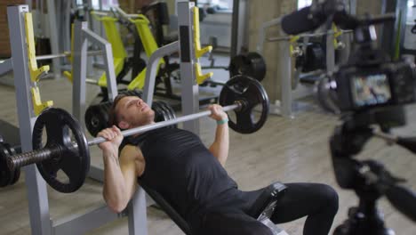 Male-Trainer-Showing-Barbell-Press-on-Camera