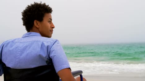 Rear-view-of-African-American-man-sitting-on-wheelchair-at-beach-4k