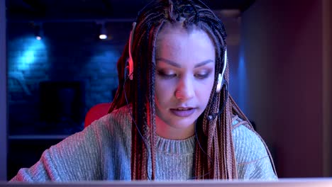 Closeup-shoot-of-young-attractive-female-blogger-with-dreadlocks-playing-video-games-and-streaming-live-with-the-neon-background-indoors