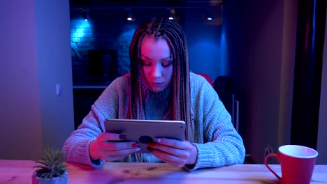 Nahaufnahme-von-jungen-attraktiven-Bloggerinnen-mit-Dreadlocks-spielen-Video-Gameson-das-Tablet-verlieren-und-frustriertes-Streaming-live-mit-dem-neon-Hintergrund-drinnen