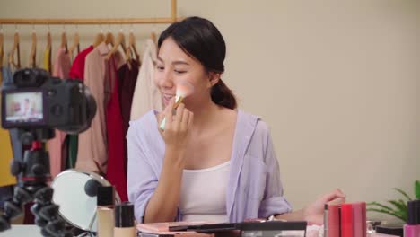 Zeitlupe---Beauty-Blogger-präsentieren-Beauty-Kosmetik-sitzen-in-der-Frontkamera-für-die-Aufnahme-von-Video.-Glückliche-schöne-junge-asiatische-Frau-verwenden-Kosmetik-Bewertung-Make-up-Tutorial-übertragen-Live-Video.