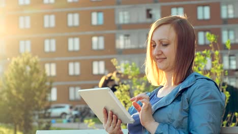 Frau-mit-Tablet-Computer-sitzt-auf-Bank-in-der-Stadt