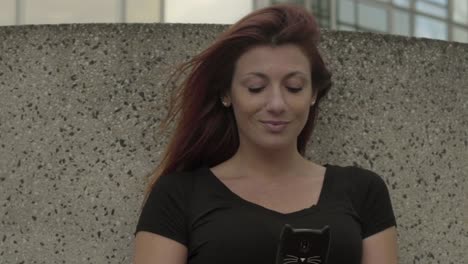 Smiling-Woman-using-smartphone-Sitting-in-business-district,-texting-with-mobile-telephone-outside,-typing-text-message-on-cell-phone.-Paris,-Red-hair.-Social-media.-4K-UHD-Slow-Motion-close-up.