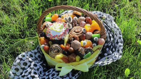 Footage-of-basket-with-Easter-cake,-dried-fruits-and-nuts-on-the-green-grass-in-garden