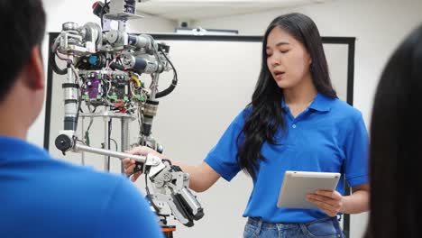 La-mujer-ingeniera-asiática-presenta-la-innovación-de-robots-con-el-equipo-de-diseño-de-arquitectos-en-laboratorio.-La-reunión-en-equipo-comparte-ideas-tecnológicas-y-un-robot-de-desarrollo-colaborador.-Concepto-de-tecnología-robótica-de-presentaci�