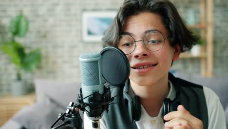 Close-up-of-happy-boy-talking-in-microphone-recording-podcast-for-blog