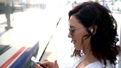 The-girl-is-waiting-for-the-train-at-the-subway-station-and-listening-to-music-on-headphones.-Use-smartphone-in-the-subway.-Underground.-Student-rides-the-subway.