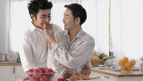 Asian-couple-gay-applying-chocolate-on-bread-in-morning-at-home.-Gay-boy-happy-emotion-and-hug-love-anniversary-together.-Concept-of-lifestyle,-family,-gay-and-bisexual.