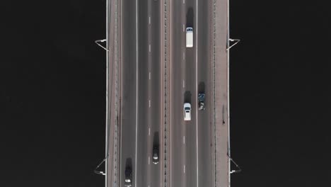 Lonely-cyclist-on-bicycle-bridge-highway-traffic-aerial-top-view-sunset