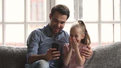 Papa-umarmen-Kind-Tochter-mit-Spaß-mit-Smartphone-auf-dem-Sofa