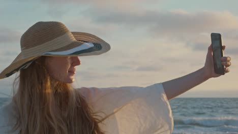 Junge-Frau-macht-ein-Selfie-am-Meer-bei-Sonnenuntergang