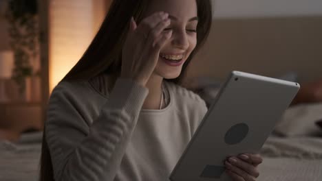 Astonished-teen-girl-using-digital-tablet-at-night