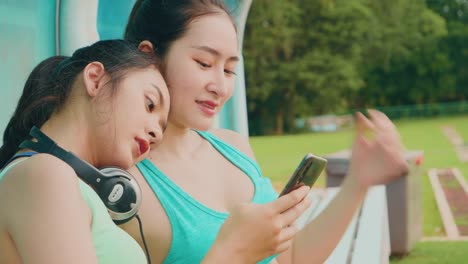 Lifestyle-asiatische-Sportfrauen-halten-Smartphone-spielen-Musik-Entspannung