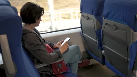 woman-is-sitting-on-train-Holding-cellphone-in-her-hands-Clicking-Rear-side-view