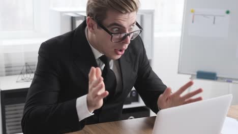 Astonished-businessman-receiving-positive-news-on-laptop