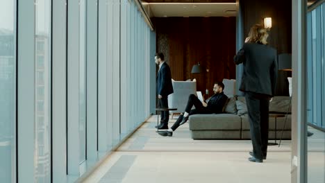 Three-men-in-black-suits-in-front-of-a-panoramic-window-of-modern-restaurant.-4K