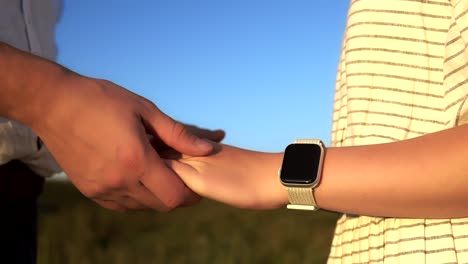 Close-up-of-caucasian-couple's-hand-in-hand-who-stand-in-a-summer-field-in-slowmo