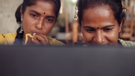 Two-women-chilling-sipping-drinks-using-technology-in-cafe