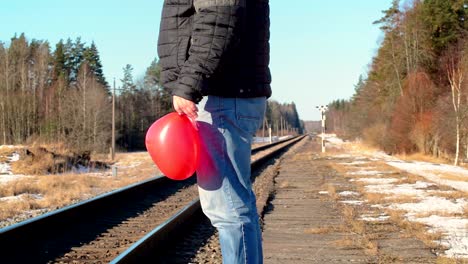 Mann-mit-roten-herzförmigen-Ballon-in-der-Nähe-der-Eisenbahn