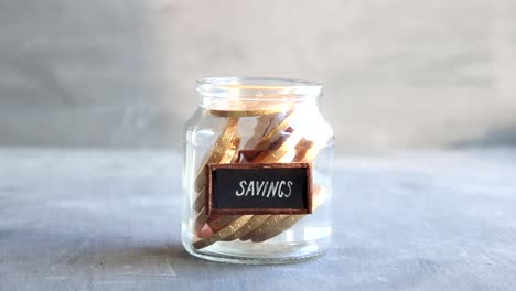 savings-idea,-vintage-tag-and-coins-in-jar