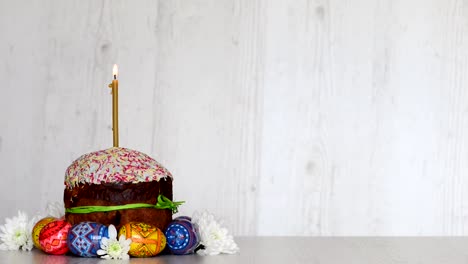 Pastel-de-Pascua-kulich-con-vela-y-huevos-en-las-flores-de-primavera-sobre-fondo-de-madera-claro