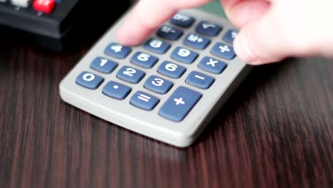 Hand-operates-old-retro-calculator-at-workstation