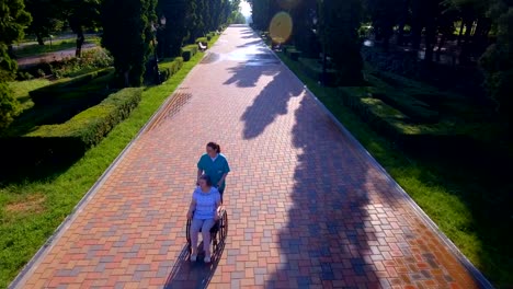 Aerial-footage-of-senior-woman-on-wheelchair-with-caring-caregiver