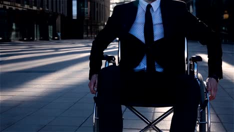 Young-businessman-move-in-wheelchair-on-camera-outdoor-near-business-centre