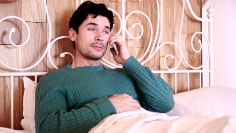 Man-Sitting-in-Bed-Dialing-call-and-Talking-on-Phone