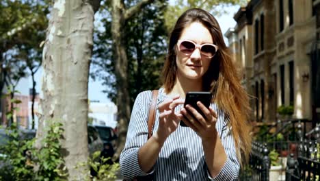 Portrait-von-junge-schöne-Frau-mit-Sonnenbrille-draußen-im-sonnigen-Sommertag-und-Smartphone-mit.-Slow-motion