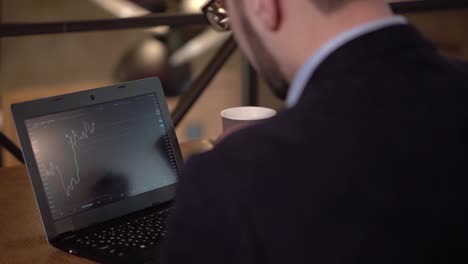 Man-in-glasses-studies-trade-graphics-on-a-laptop-while-sitting-in-a-cafe