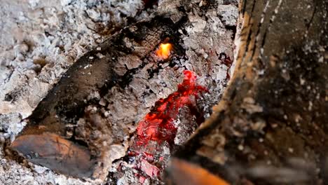 Smoldering-fire-coals-in-ruined-old-house-among-stones-bricks,-abandoned-area