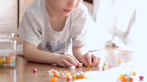 süsser-Boy-spielen-mit-bunten-Bonbons