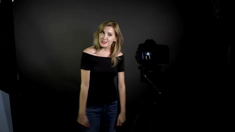 Young-blonde-Bloggerin-Aufnahme-Vlog-Nachricht-für-ihre-Abonnenten-in-einem-professionellen-Studio-lächelnd