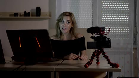 Blonde-attractive-female-video-blogger-filming-herself-with-a-camera-at-office-teaching-audience-how-to-analyze-traffic-data