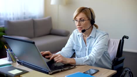 Disabled-female-manager-sitting-at-office-desk,-working-on-laptop-from-home