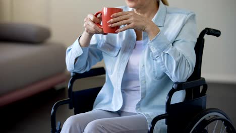 Senior-woman-in-wheelchair-drinking-tea,-pensioner-relaxing-at-home,-leisure