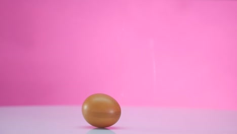 The-egg-spins-on-a-table-on-a-pink-background