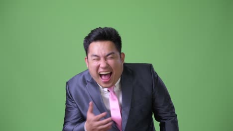 Young-handsome-overweight-Asian-businessman-against-green-background