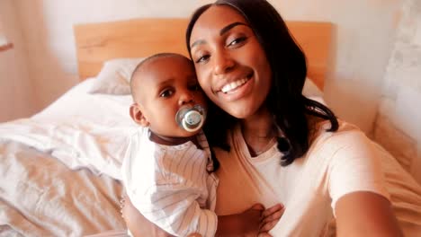 Happy-young-mother-with-little-son-taking-selfies-at-home