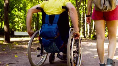 Ruedas-de-una-silla-de-ruedas-y-piernas-de-la-mujer-durante-la-caminata