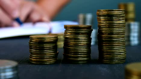 Man-makes-notices-in-a-notepad-and-stack-of-coins.-Budgeting-and-making-a-savings.