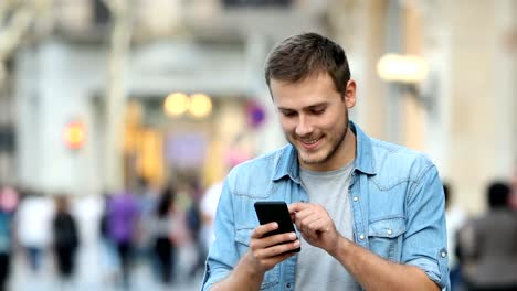 Hombre-caminando-y-usando-un-teléfono-inteligente-en-la-calle