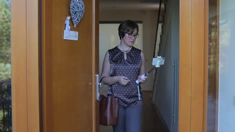 woman-at-the-entrance-to-house-with-a-selfie-stick