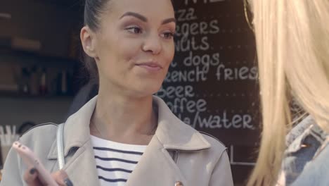 Young-woman-talking-with-her-friend-outdoor-cafe