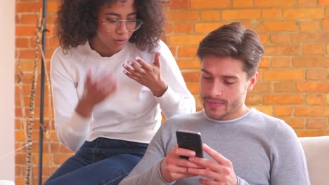 Couple-using-mobile-phone-on-sofa-at-home