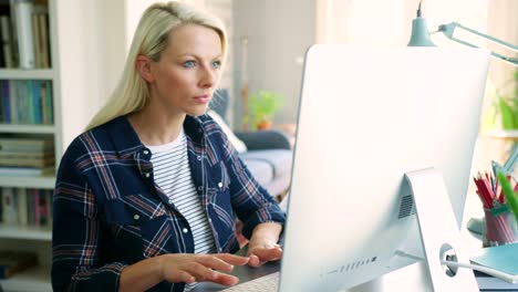 Schöne-blonde-Geschäftsfrau-tippen-am-Computer-zu-Hause-Büro