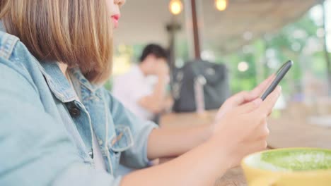 Freie-asiatische-Geschäftsfrau-mit-Smartphone-zum-sprechen,-lesen-und-SMS-beim-Sitzen-am-Tisch-im-Café.-Lebensstil-smart-schöne-Frauen-arbeiten-bei-Coffee-Shop-Konzepte.